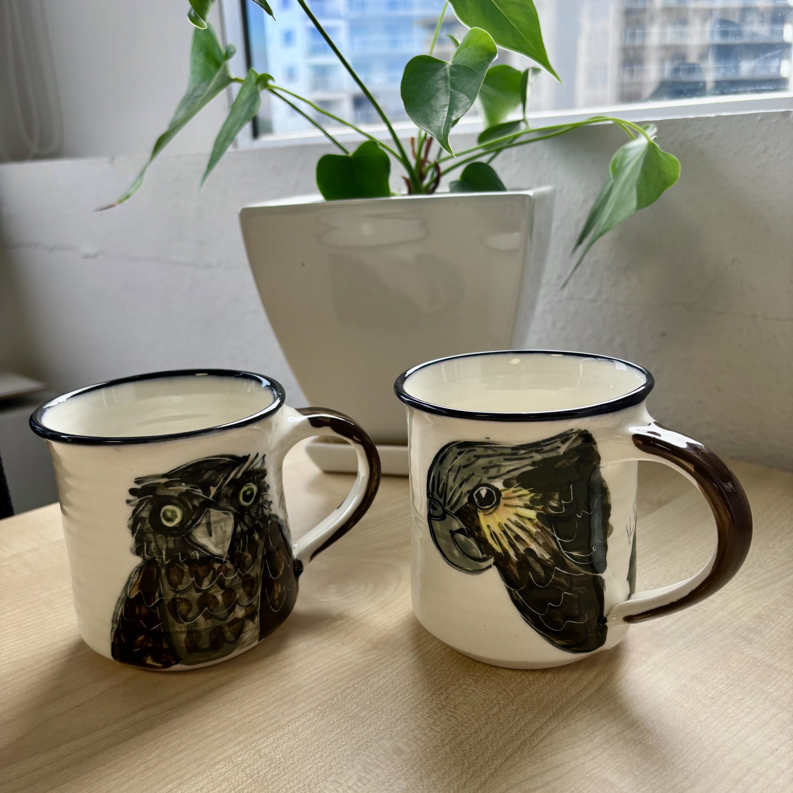 Two mugs, one depicting ruru bird the other depicting kaka bird
